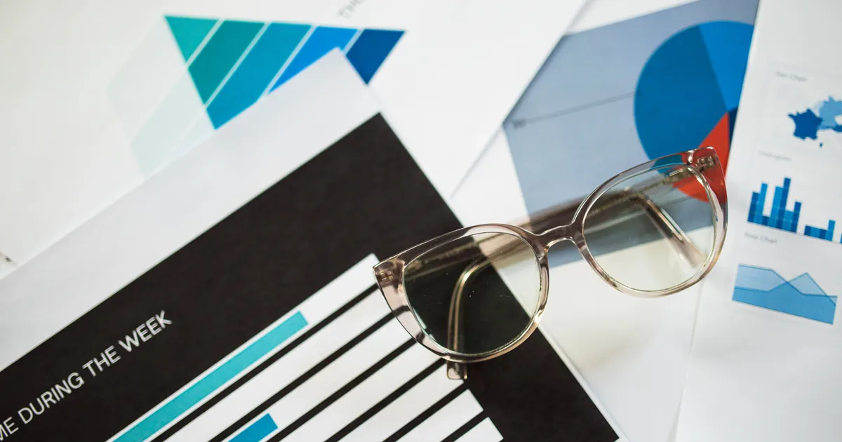 Informes impresos con gráficos y unas gafas sobre un escritorio